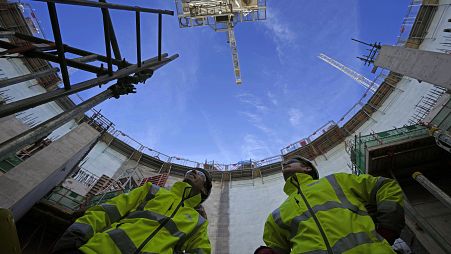 Employees look up at the construction site of Hinkley Point C nuclear power station in Somerset, England, Tuesday, Oct. 11, 2022.